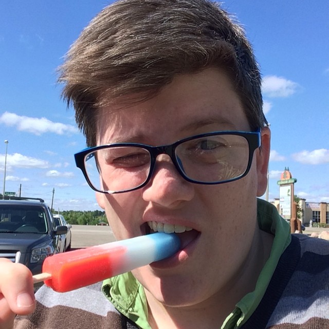 a young man wearing glasses brushing his teeth