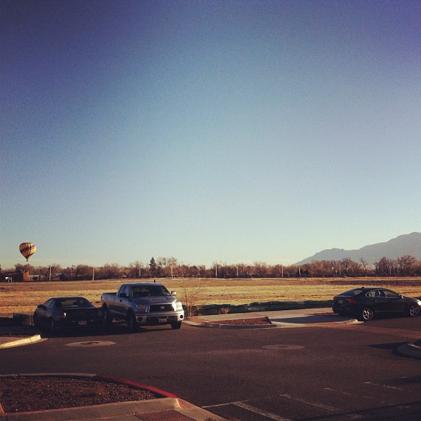 some cars are parked by some water and a  air balloon