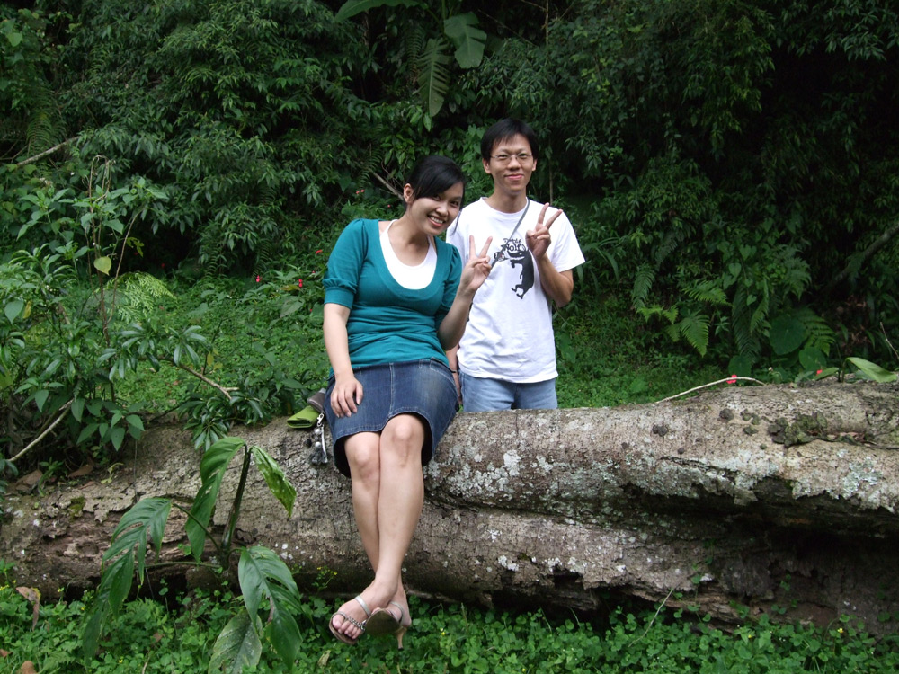 a man and woman sitting on a tree log in the woods