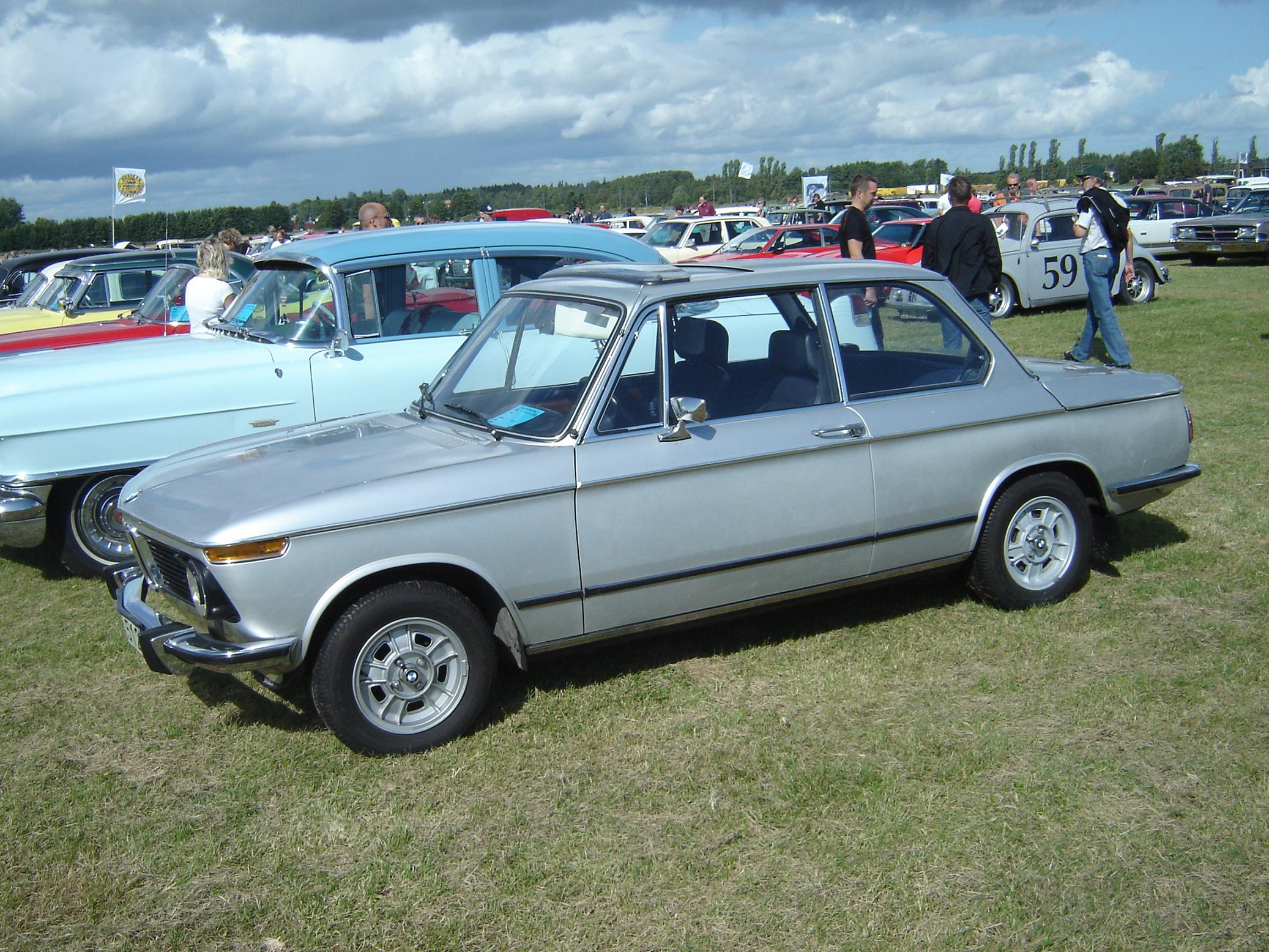 an older car is parked in the middle of a field