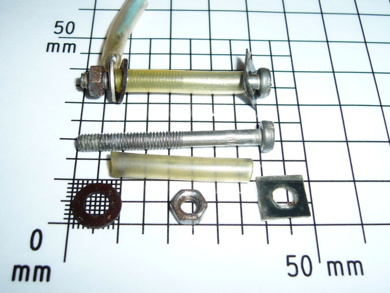 different parts of screw and nut on top of a ruler