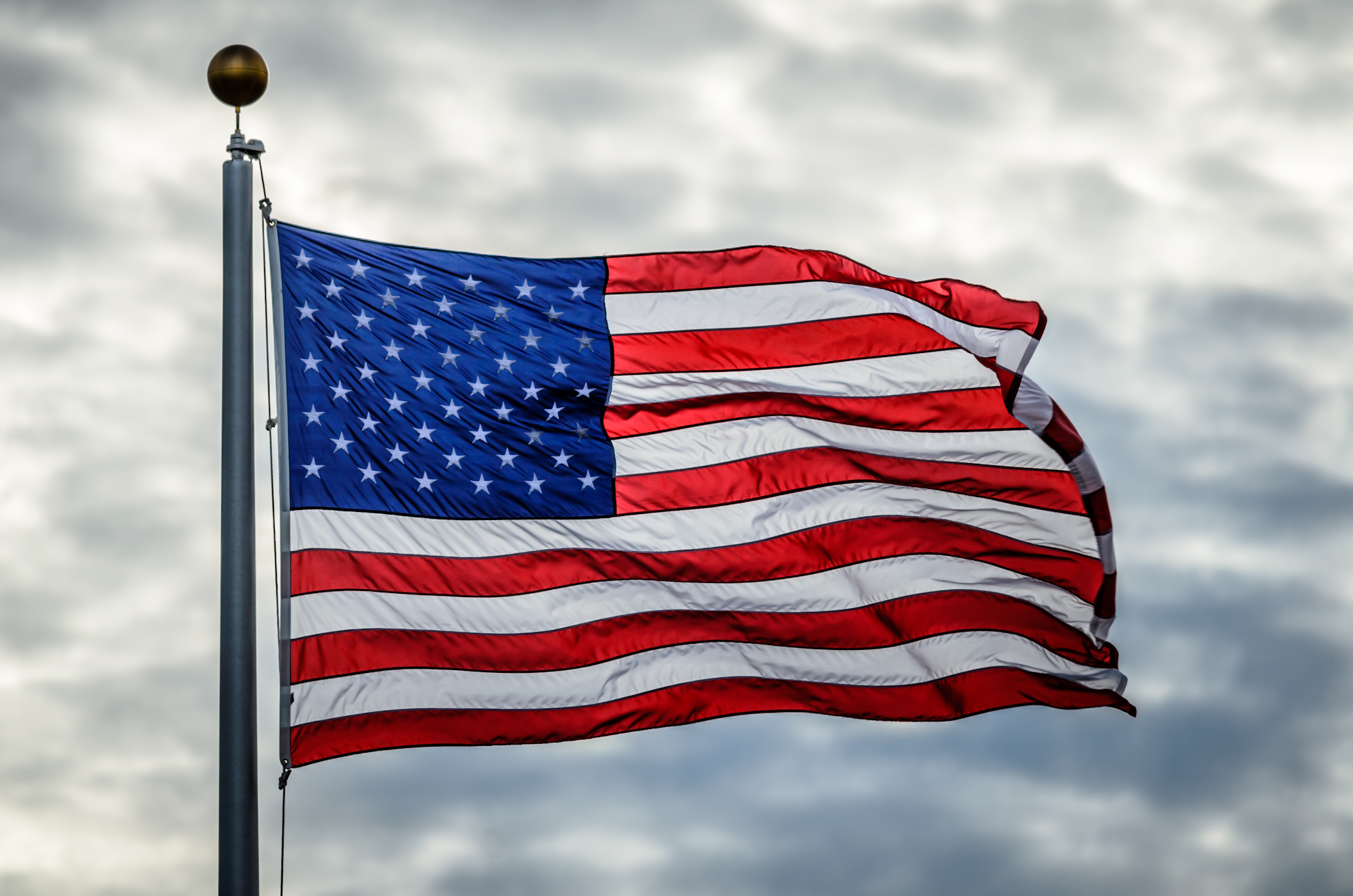 an american flag flying in a cloudy sky