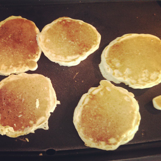 four pancakes sitting on a pan and one is half eaten