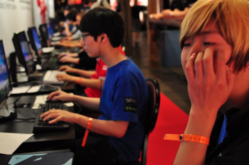 two boys are sitting at a table in front of computers