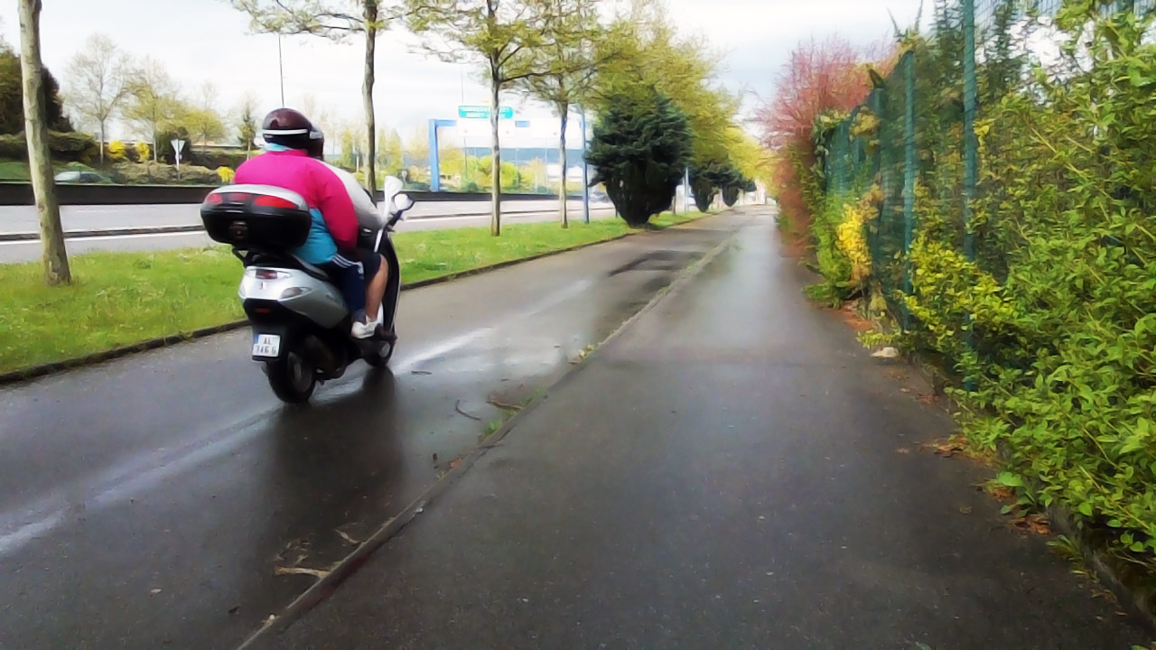 the motorcycle rider rides down the rainy street