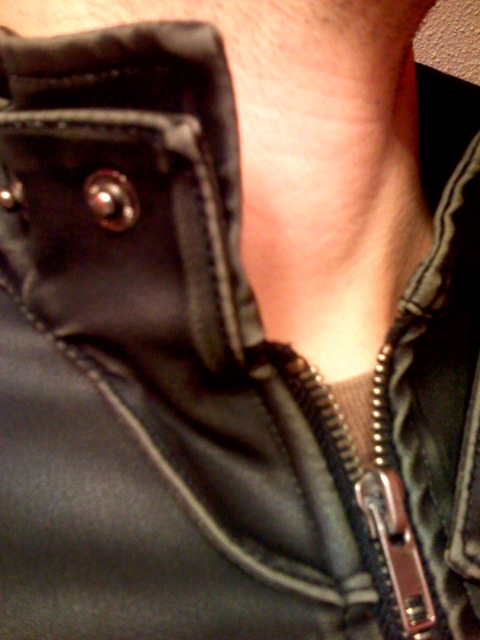a close up of a man's neck, showing a metal zipper on the collar and inside of his shirt