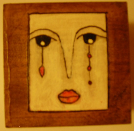 a wooden square with an artistic picture of a woman's face