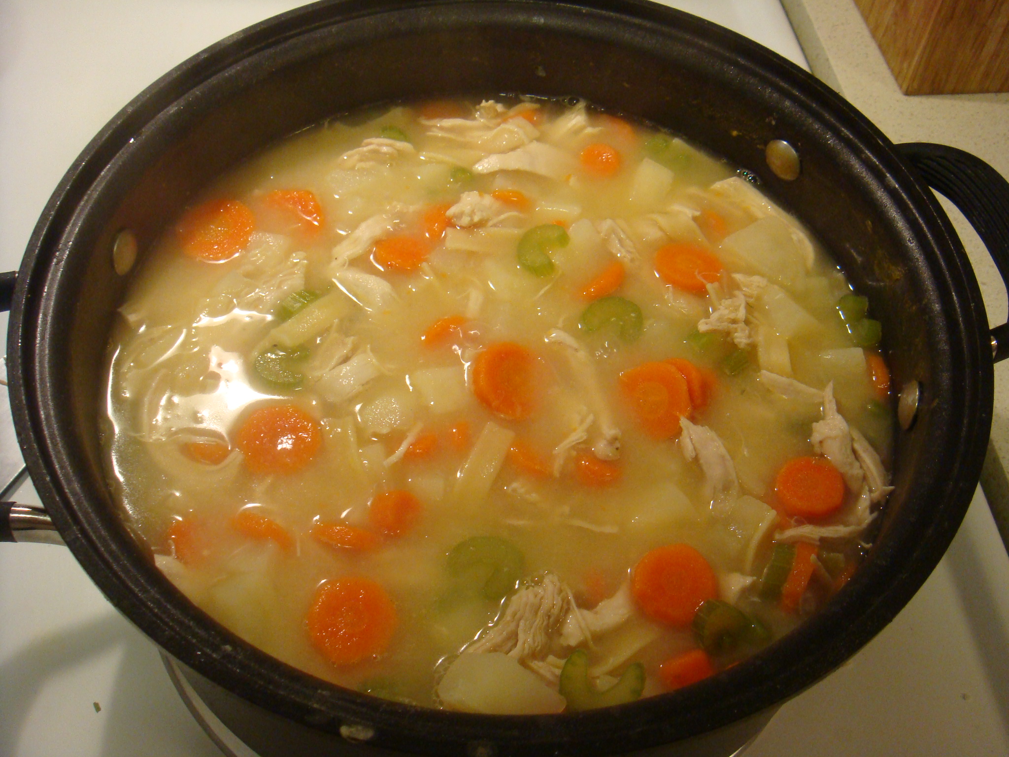 a pot of soup with carrots, celery and chicken