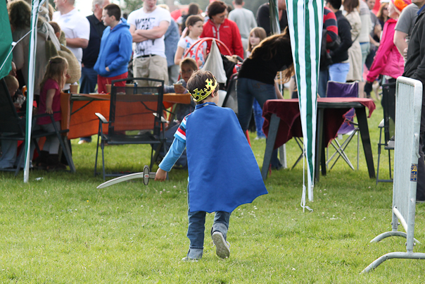 small child in cape and boots playing frisbee