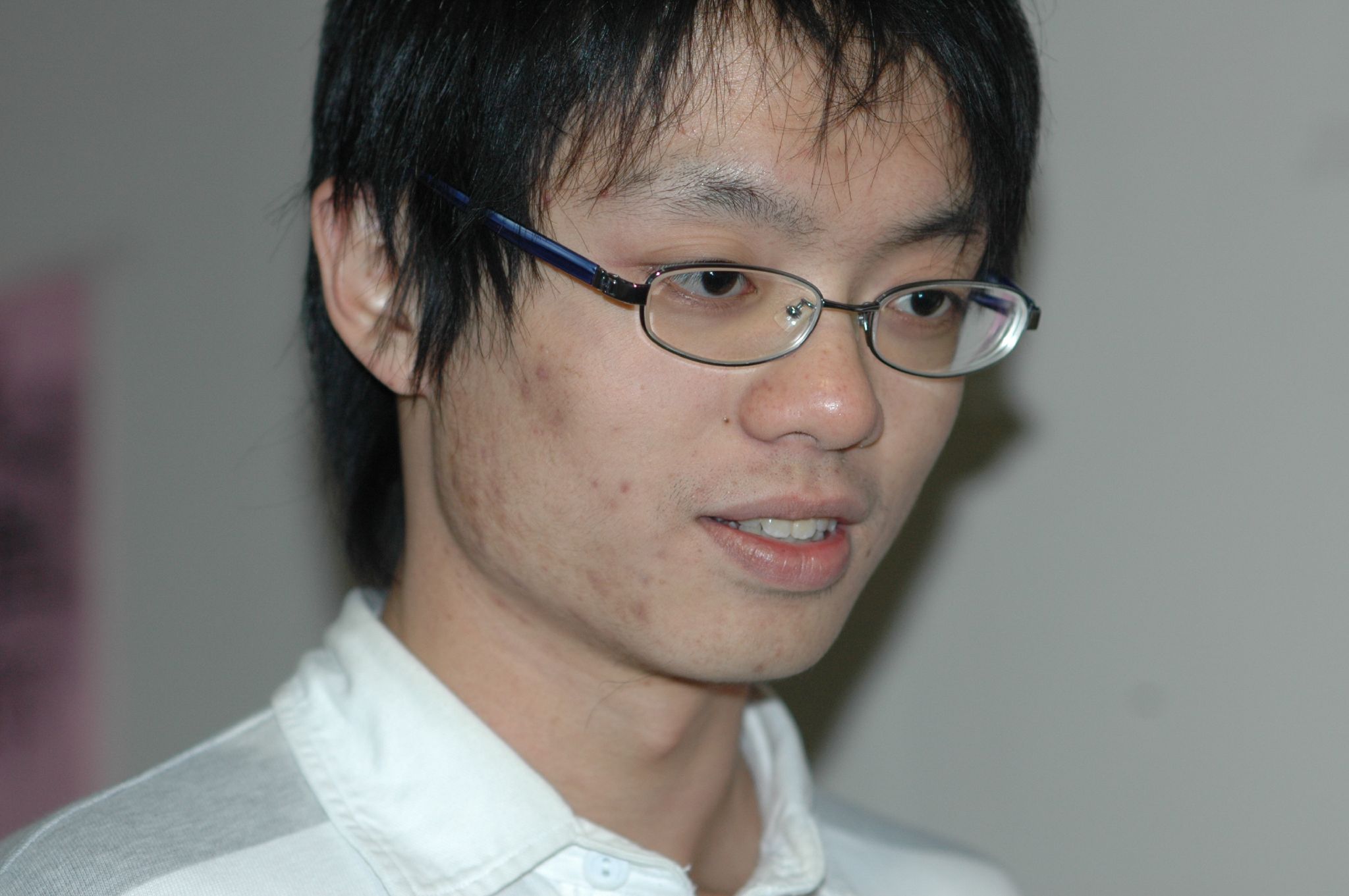 asian man with glasses looking off into the distance