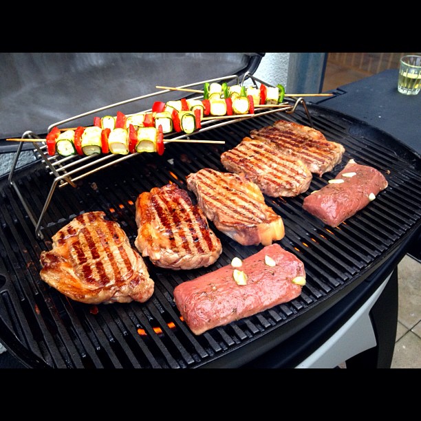 hamburgers and steaks cooking on the grill outdoors