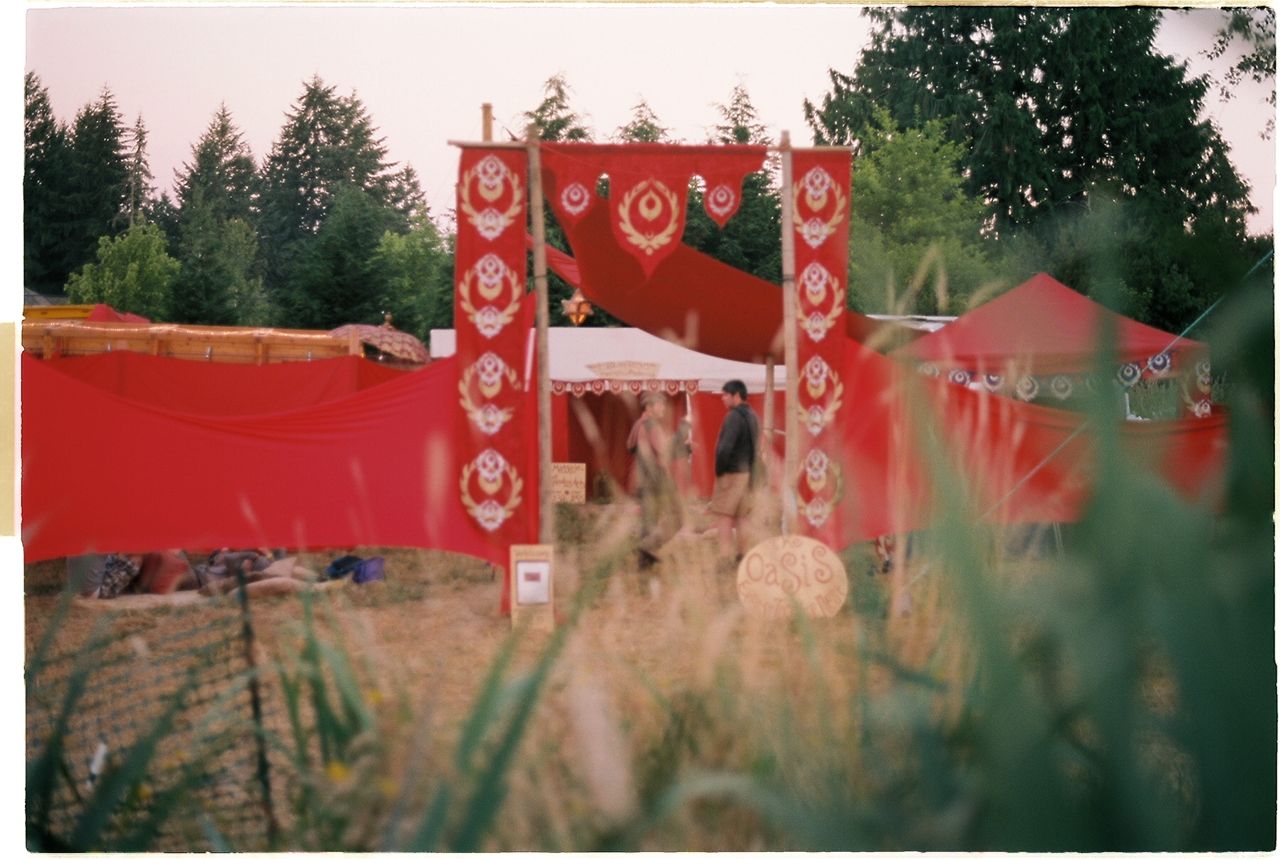 a number of tents in a field with people and flags