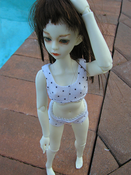 a small doll posed near the pool for an awkward po