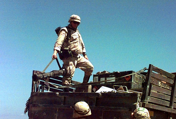 two soldiers walking on top of a truck on the beach