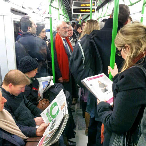 people in subway car reading newspapers and standing