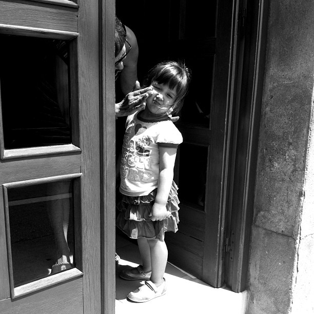 a black and white po of a little girl standing by a door