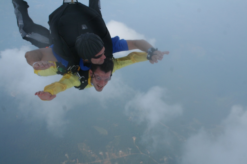 two men are skydiving above the clouds and land