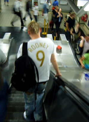 a man wearing a backpack is walking down an escalator