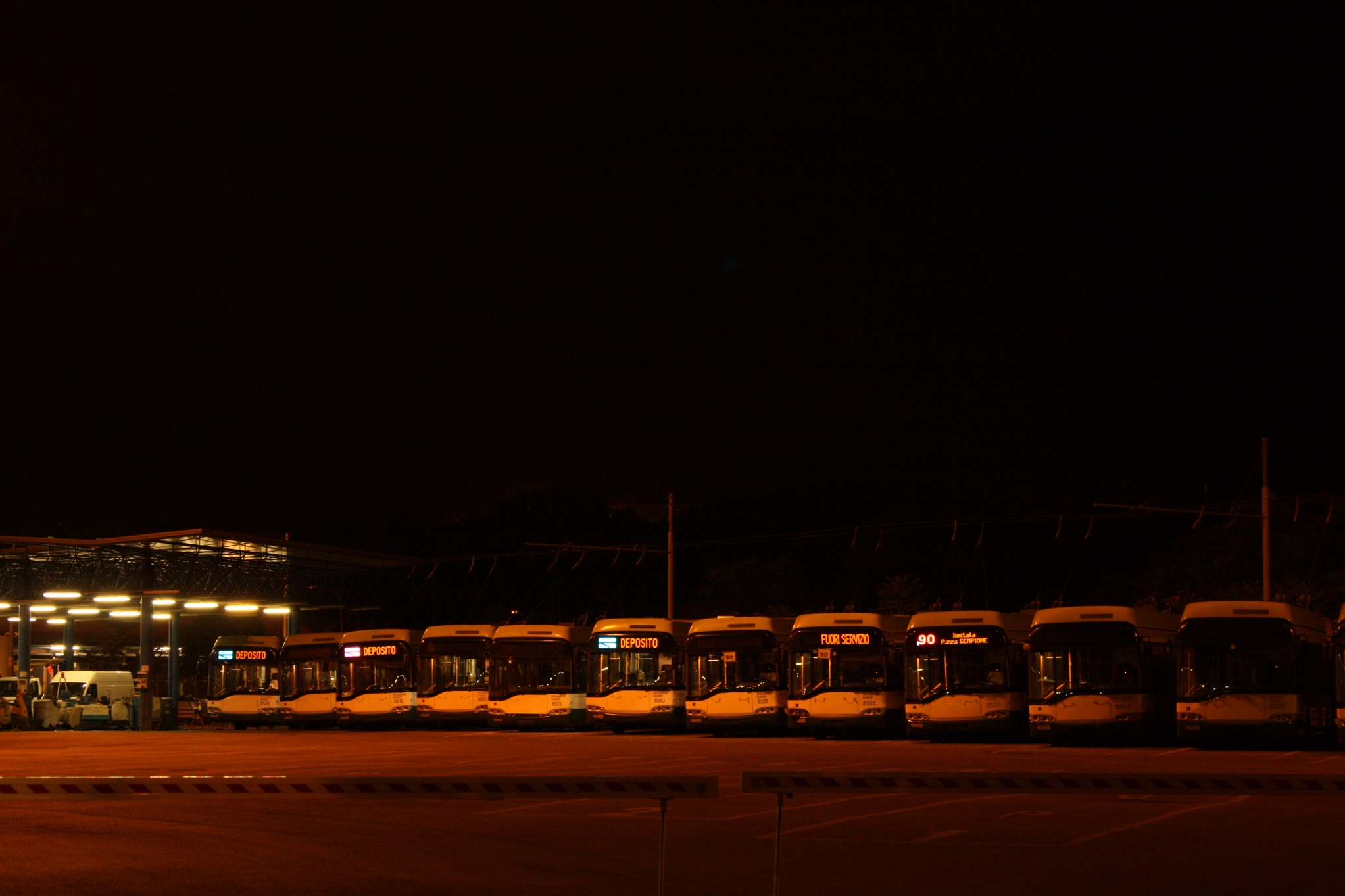 a bus yard at night with lots of buses parked