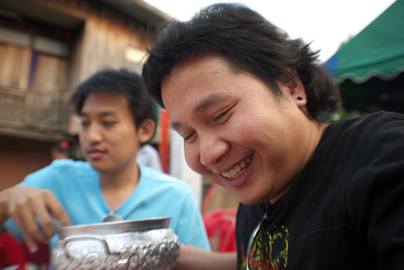 a young man laughing as he cuts a piece of cake