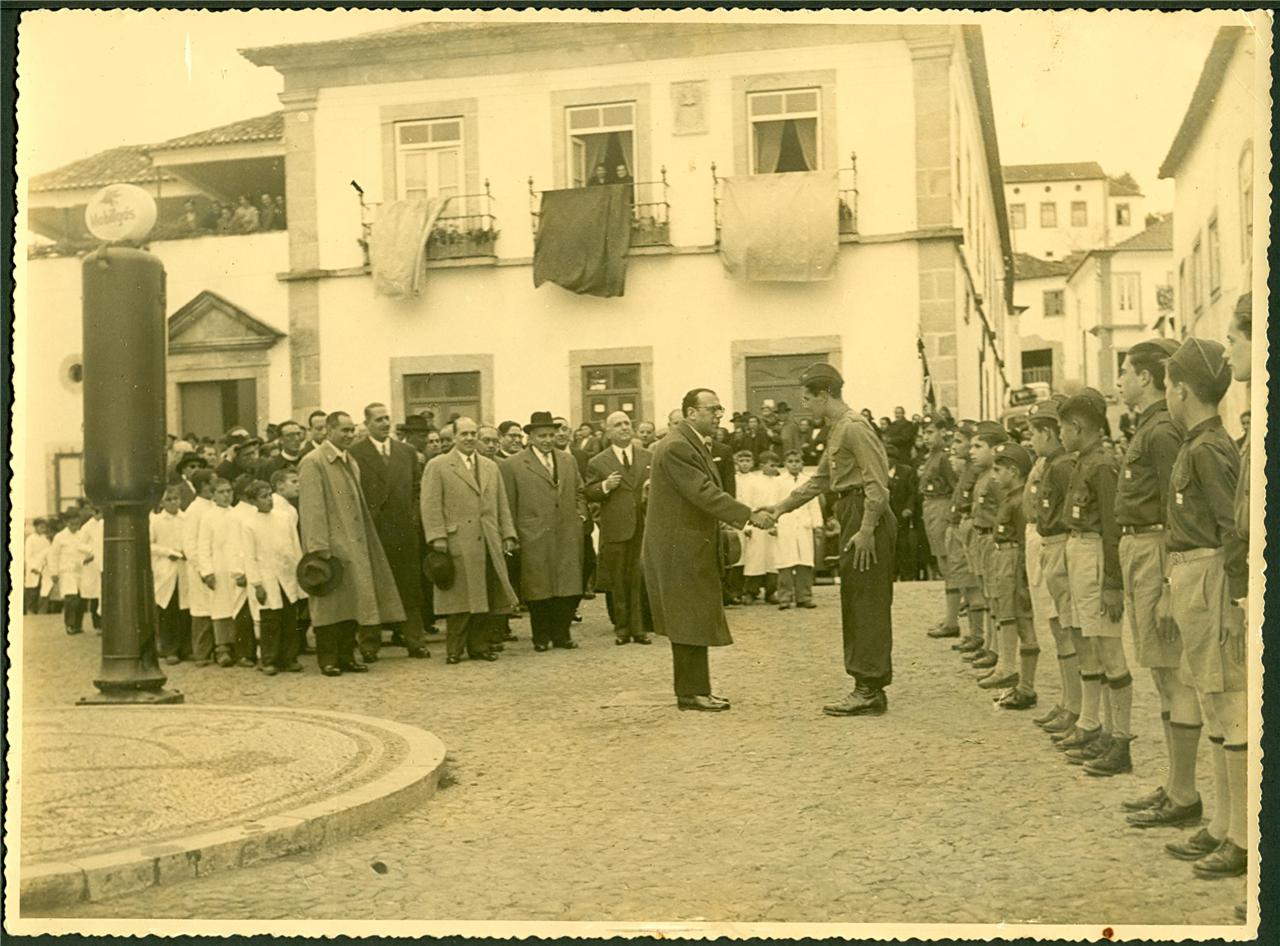 people standing outside a building watching a soldier shake hands