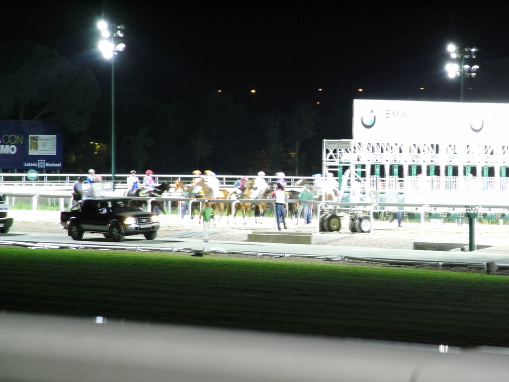 the night sky over a track and spectators with a car driving past