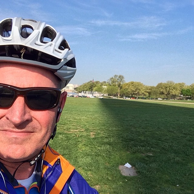 a man with a bicycle helmet and glasses standing in front of the camera