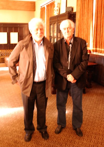 two older men standing next to each other in a lobby