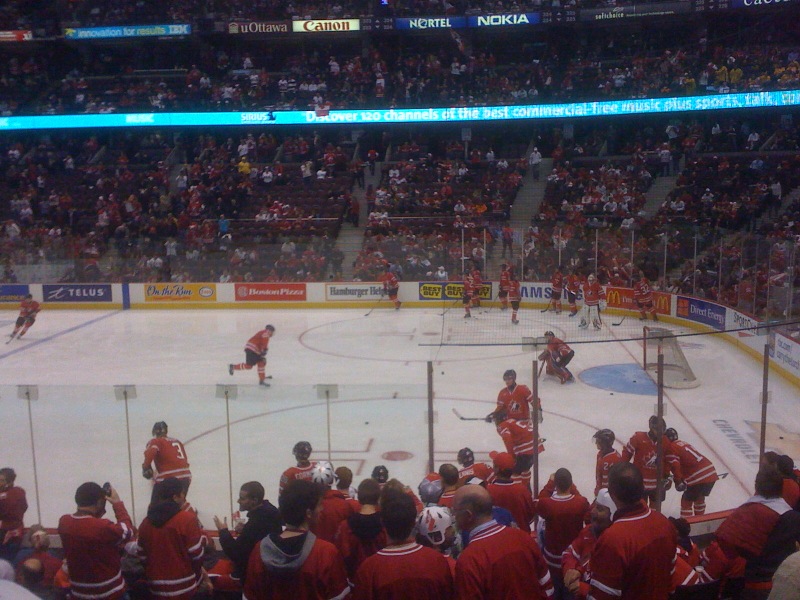 hockey fans in red gather around the ice for an audience