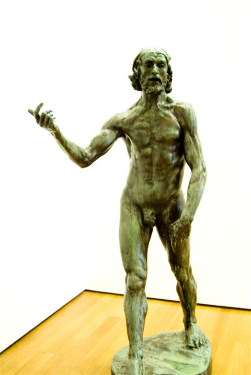 a bronze statue of a man standing on top of a wooden floor