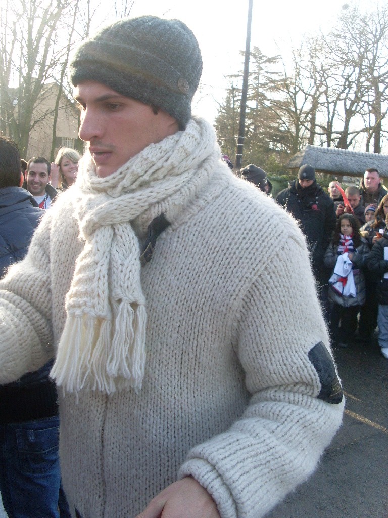 a man in a sweater and hat with some people behind him