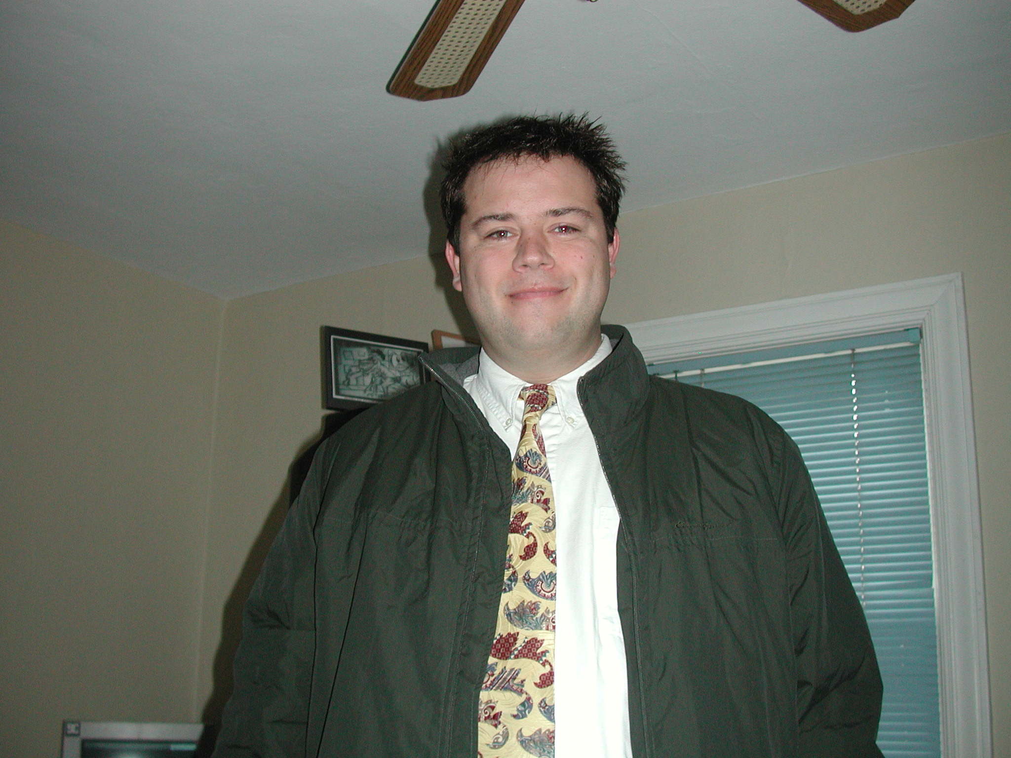 a man is standing with a jacket, tie and glasses