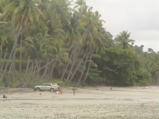 there is a small suv that is driving around the beach