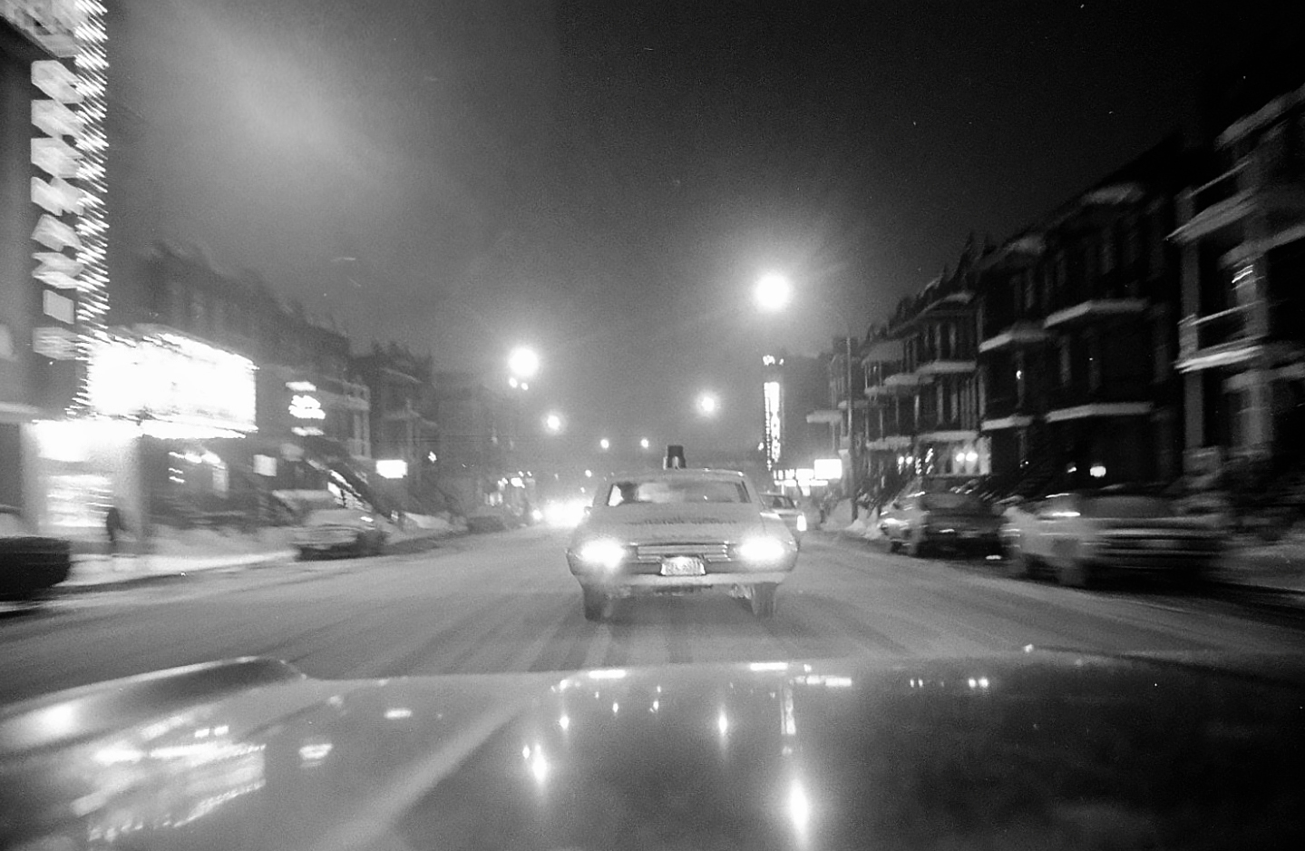 a black and white picture of the street with cars on it