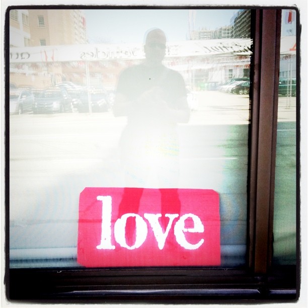a red piece of wood sits in front of a window with the word love spelled on it