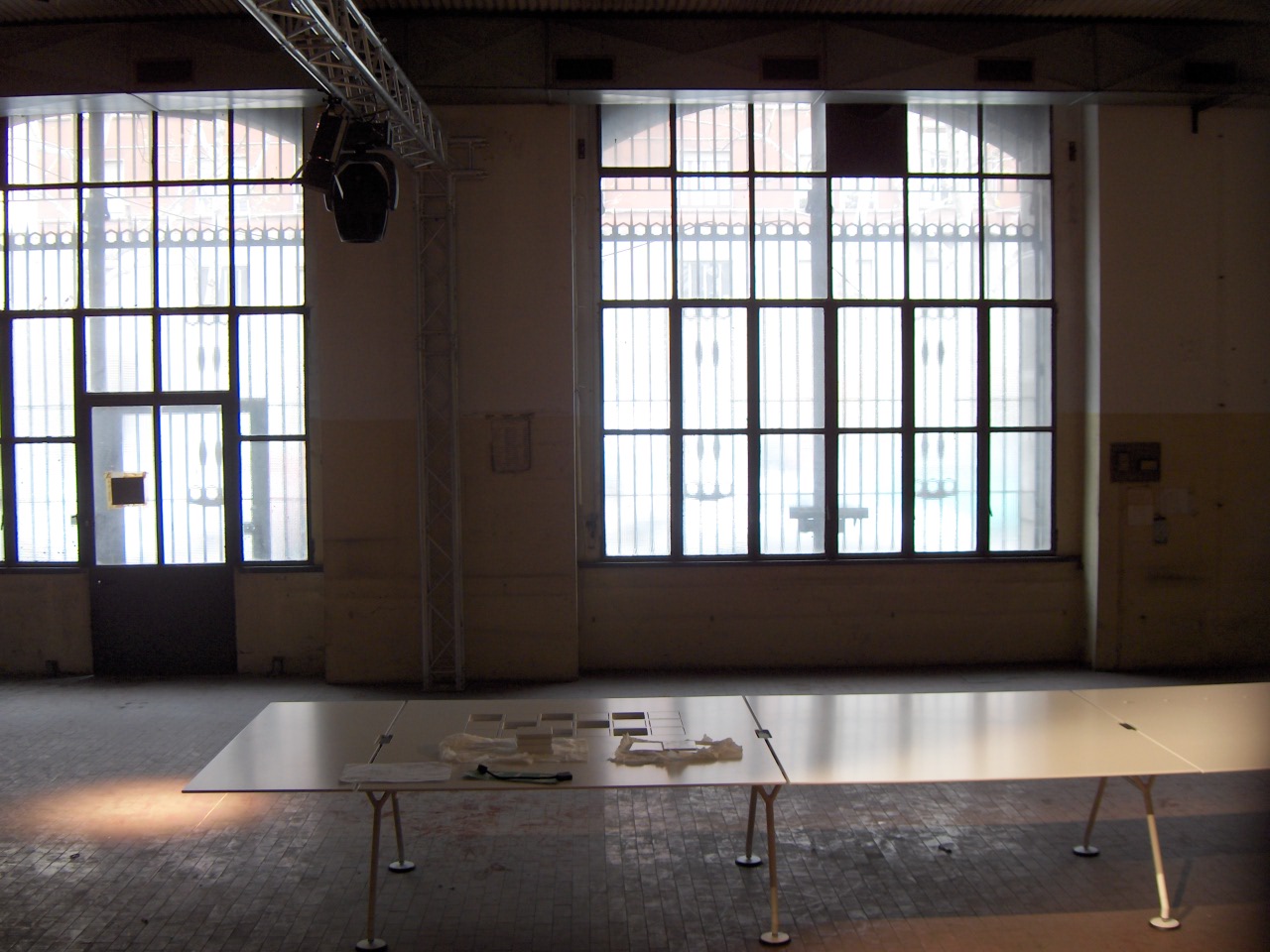 a long table sits in an empty room with lots of windows