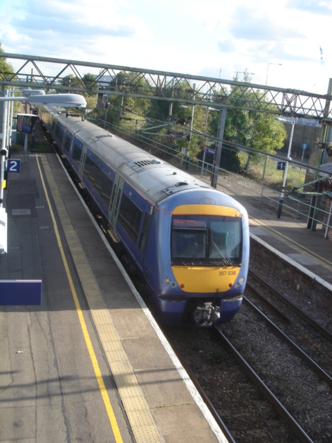 a commuter train pulling into a station next to a loading platform