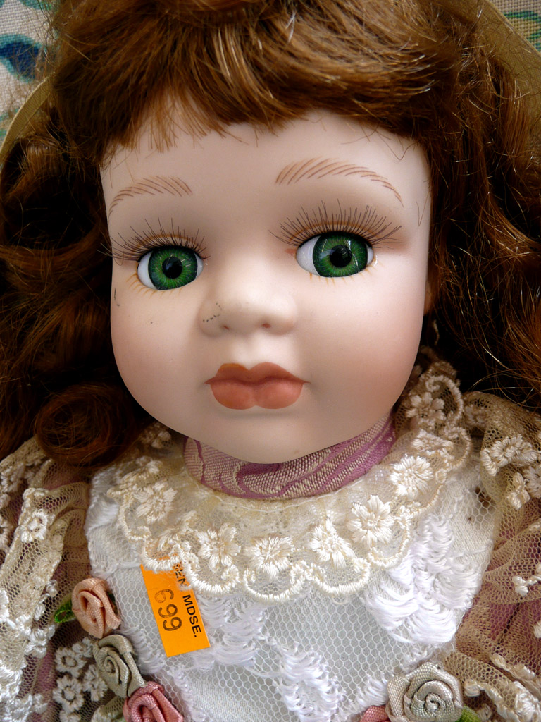 an old porcelain doll has brown hair and green eyes