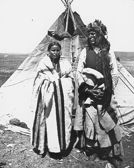 two indian men pose for a pograph in front of their teepee