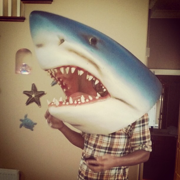 a man is holding up a shark mask