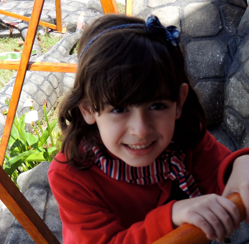 a girl sitting outside with a bat and smiling