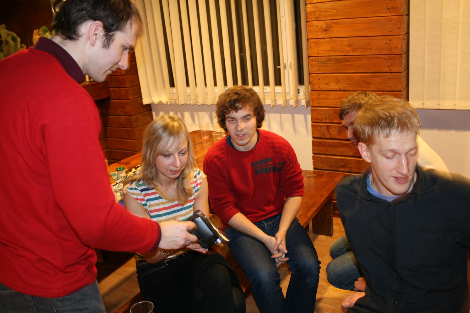 a group of young adults sit on the floor with remote controls
