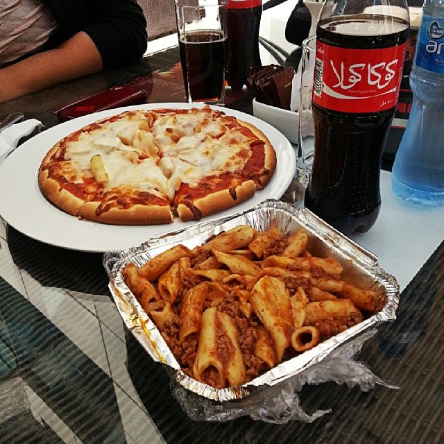 some pizzas and pasta sit on trays