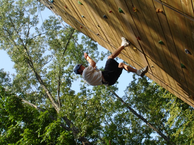 a man on a rope course holding onto the wall
