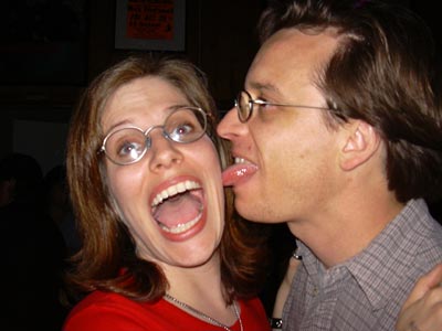 a man standing next to a woman with her tongue out
