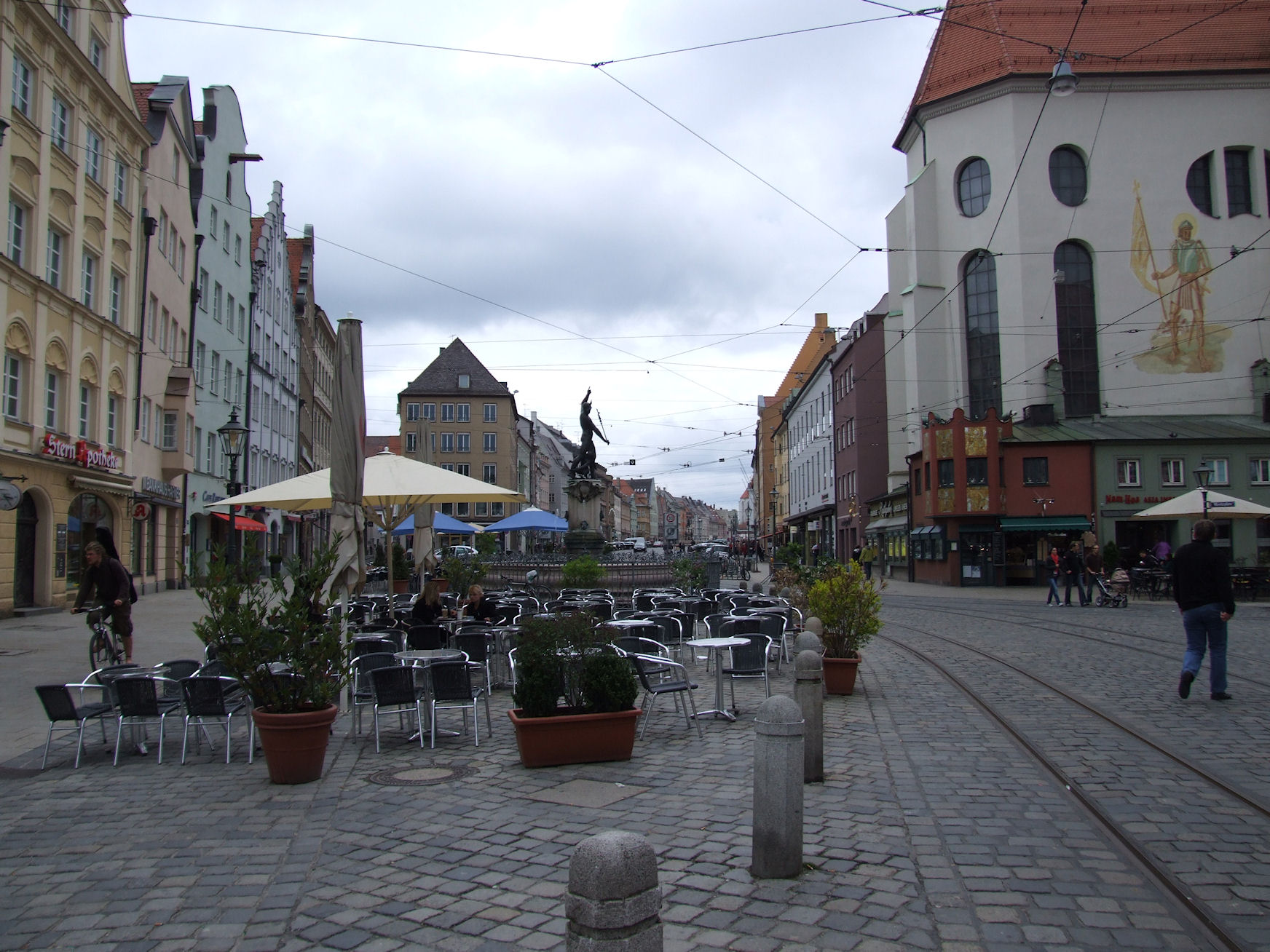 an empty street is lined with buildings, tables and chairs