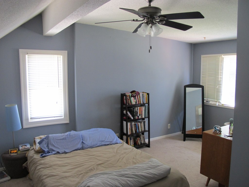 a very big room with a fan and a bed