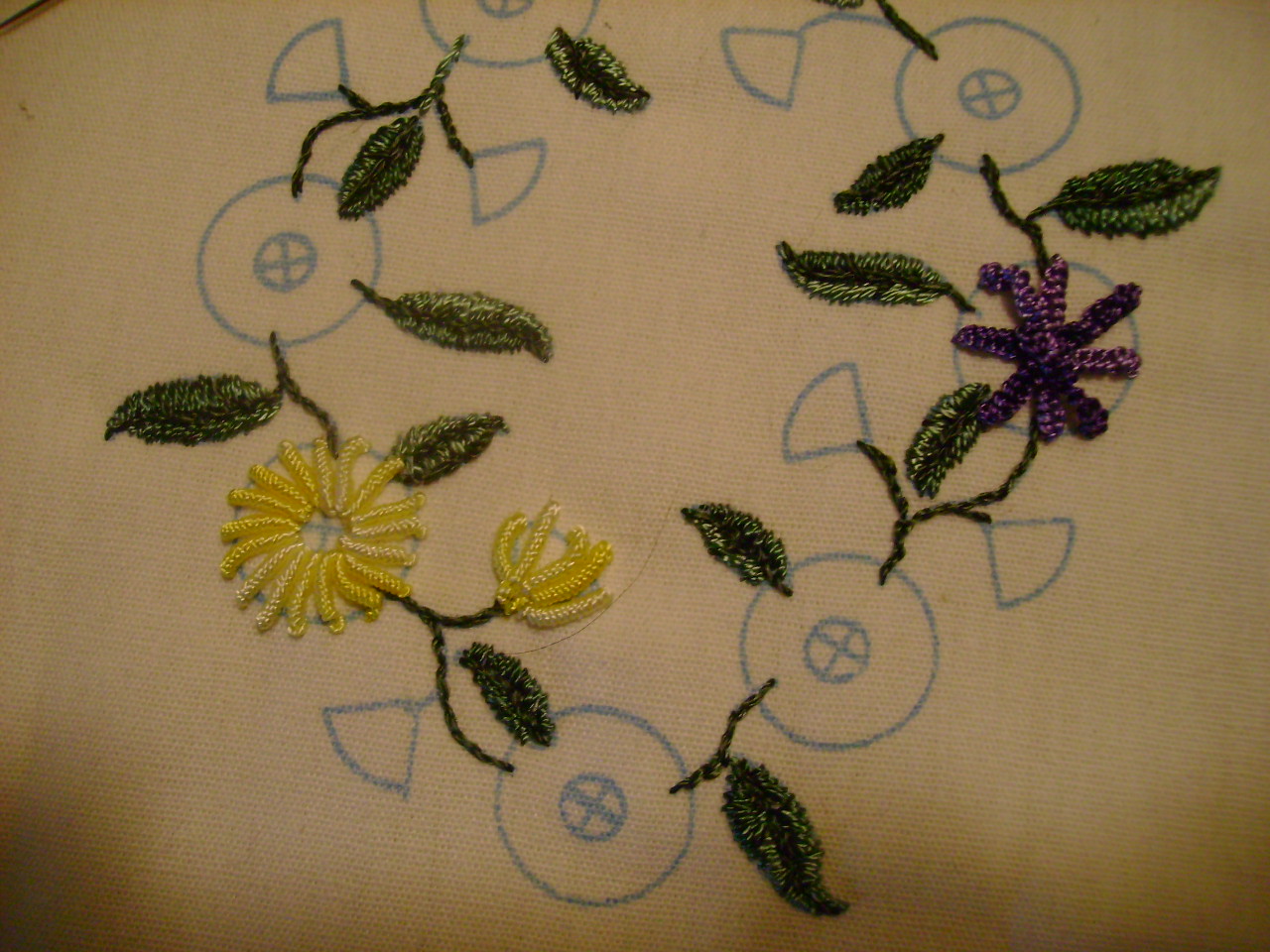 a pair of embroidered flowers laying on top of a piece of fabric
