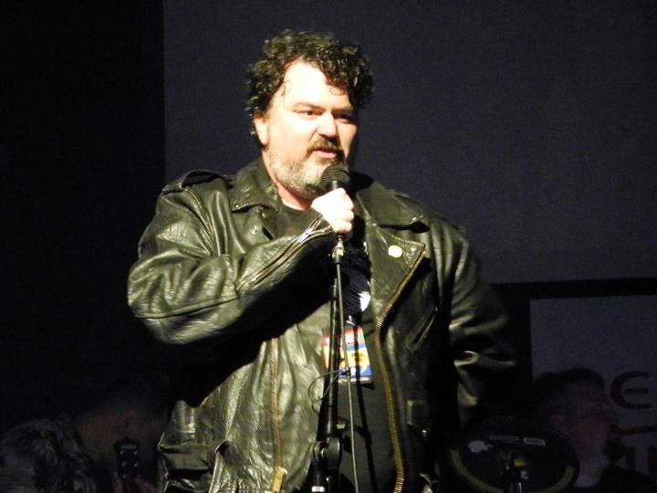 a man wearing a leather jacket holding a microphone