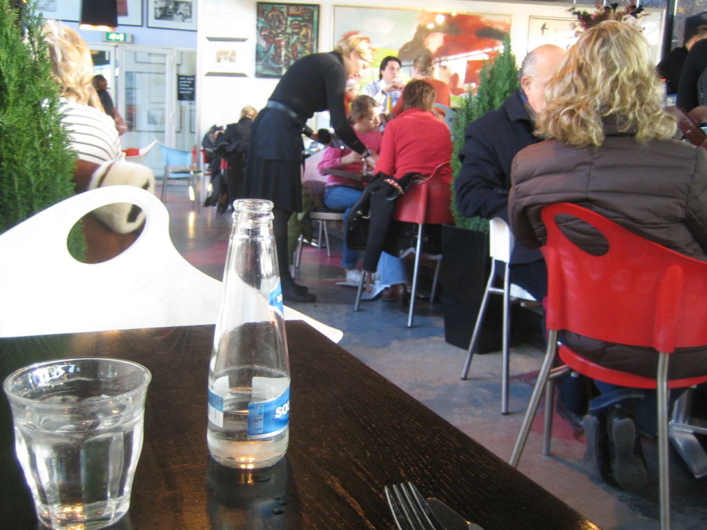 people sitting at tables outside in a restaurant with lots of chairs